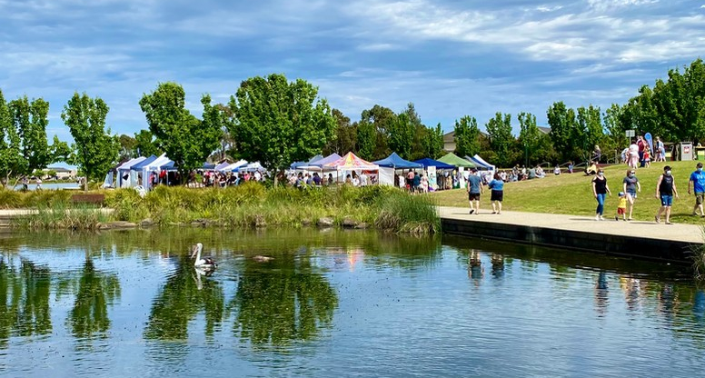 People walking by lake with market in background